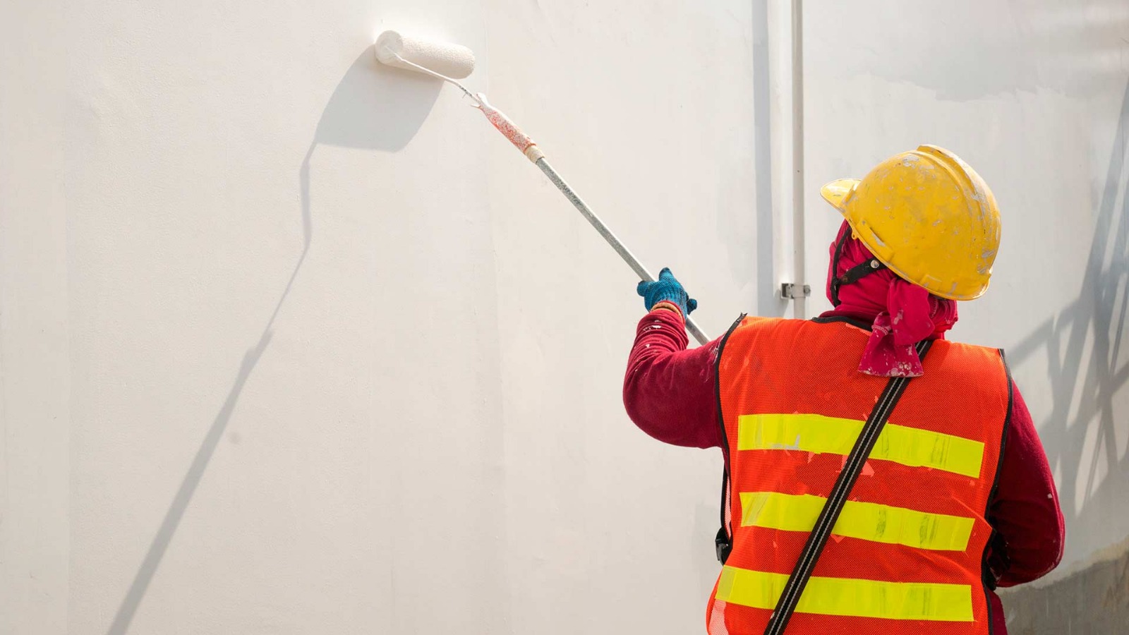 Painter using a roller to paint an exterior wall