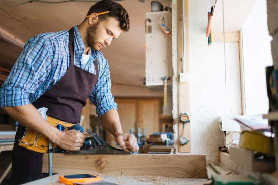 Carpenter measuring and cutting timber on site