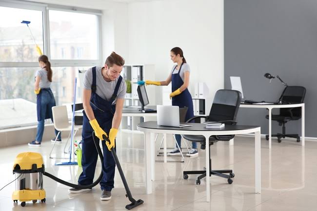 Gloved hand applying hospital-grade disinfectant to an office surface