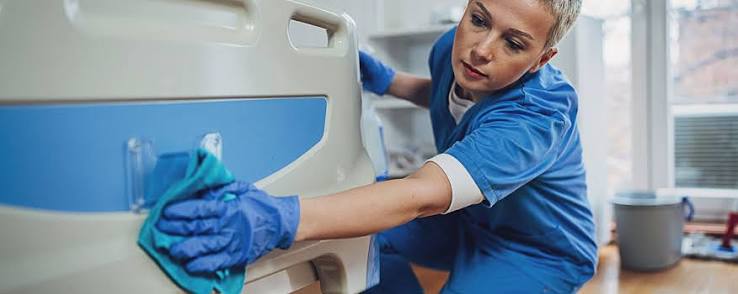 Gloved hands disinfecting clinical equipment